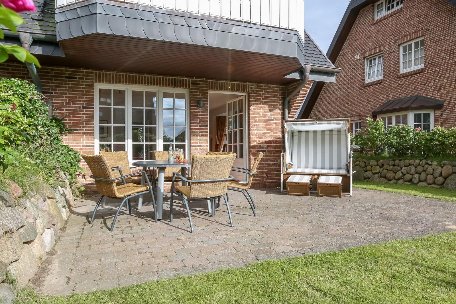 Terrasse mit Sitzgruppe und Strandkorb vor Backsteinhaus