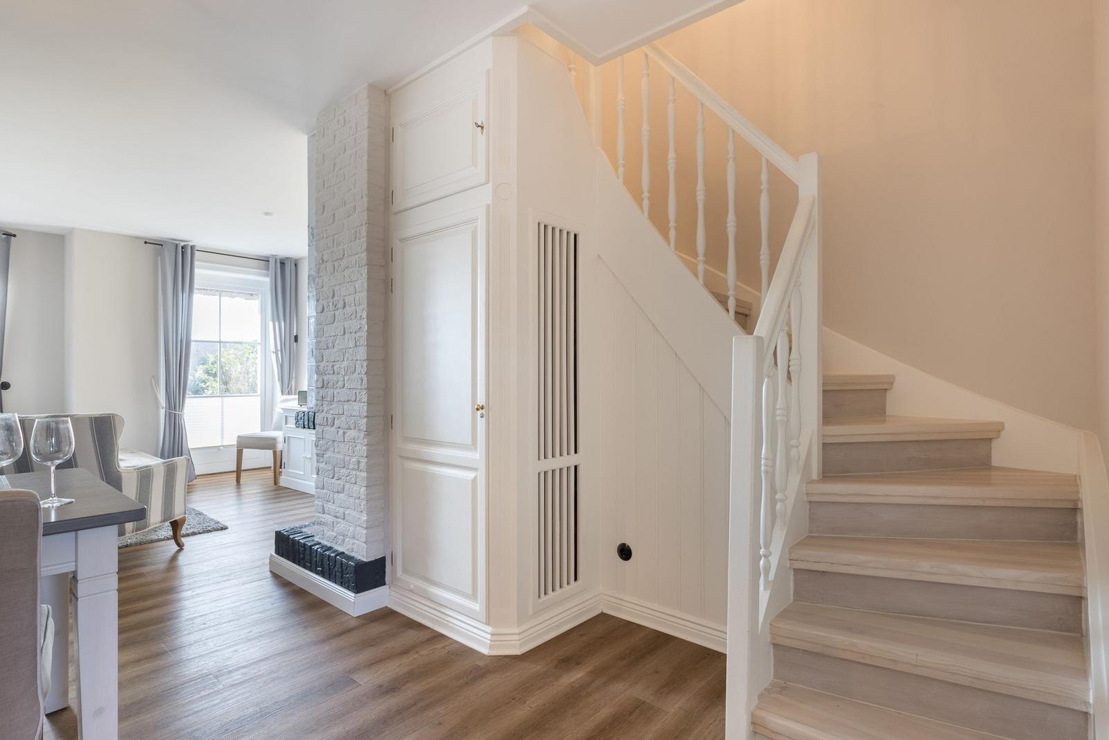 Treppenhaus mit weißer Treppe und integriertem Schrank neben Steinwand