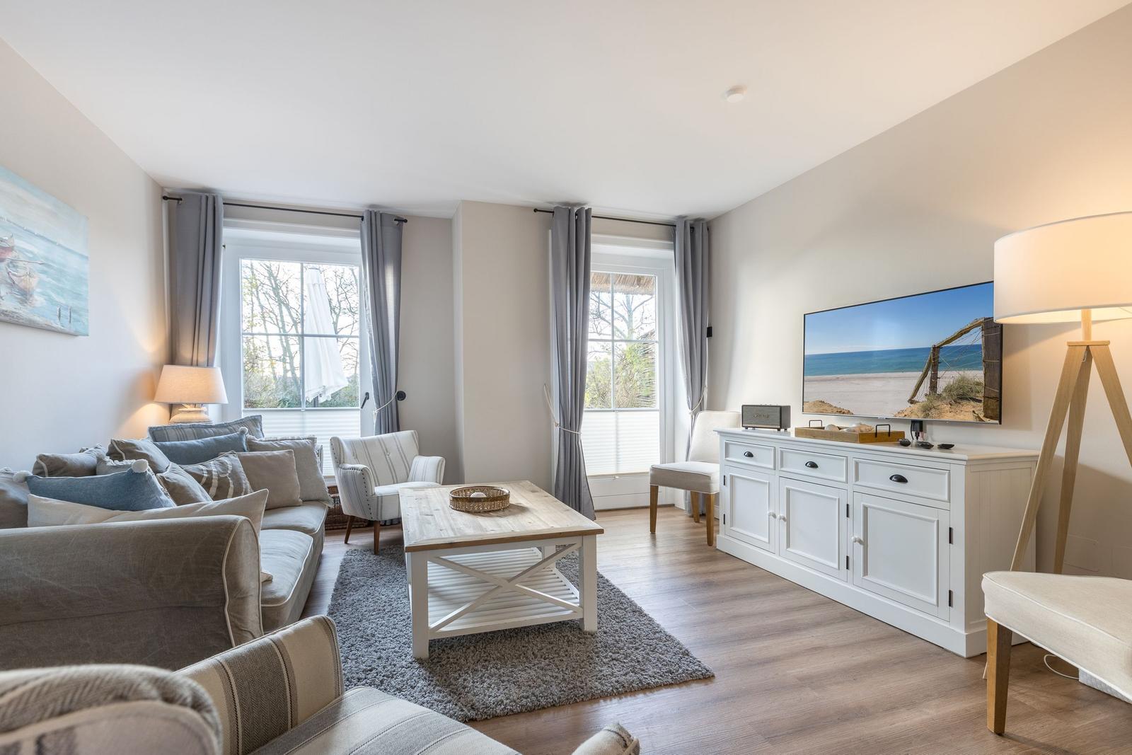 Wohnzimmer mit Sofa, Couchtisch und Fernseher an weißem Schrank