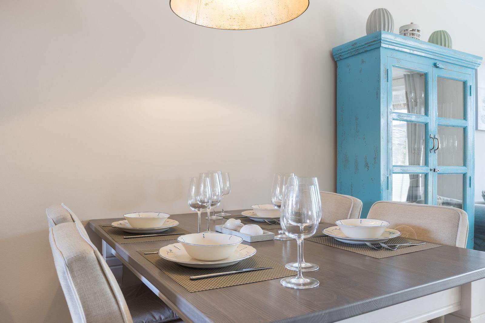 Esstisch mit Stühlen, Geschirr und blauem Schrank.