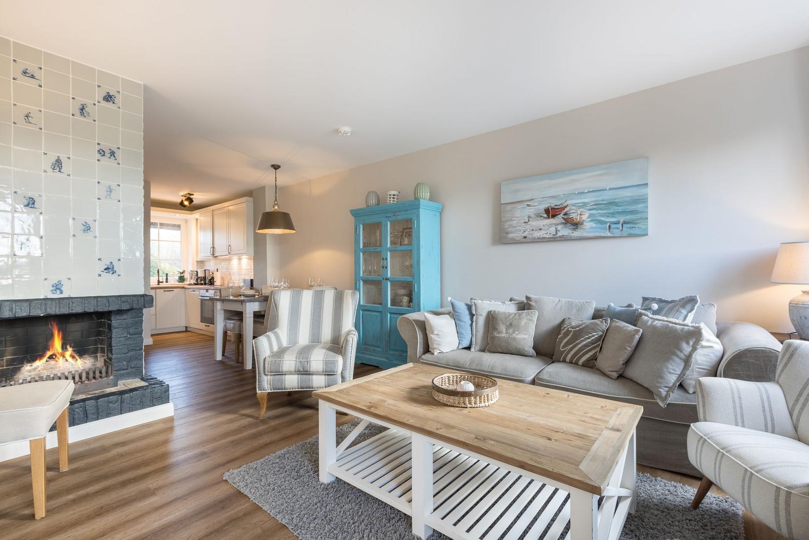 Wohnzimmer mit Kamin, Sofa und Küchenbereich im Hintergrund.