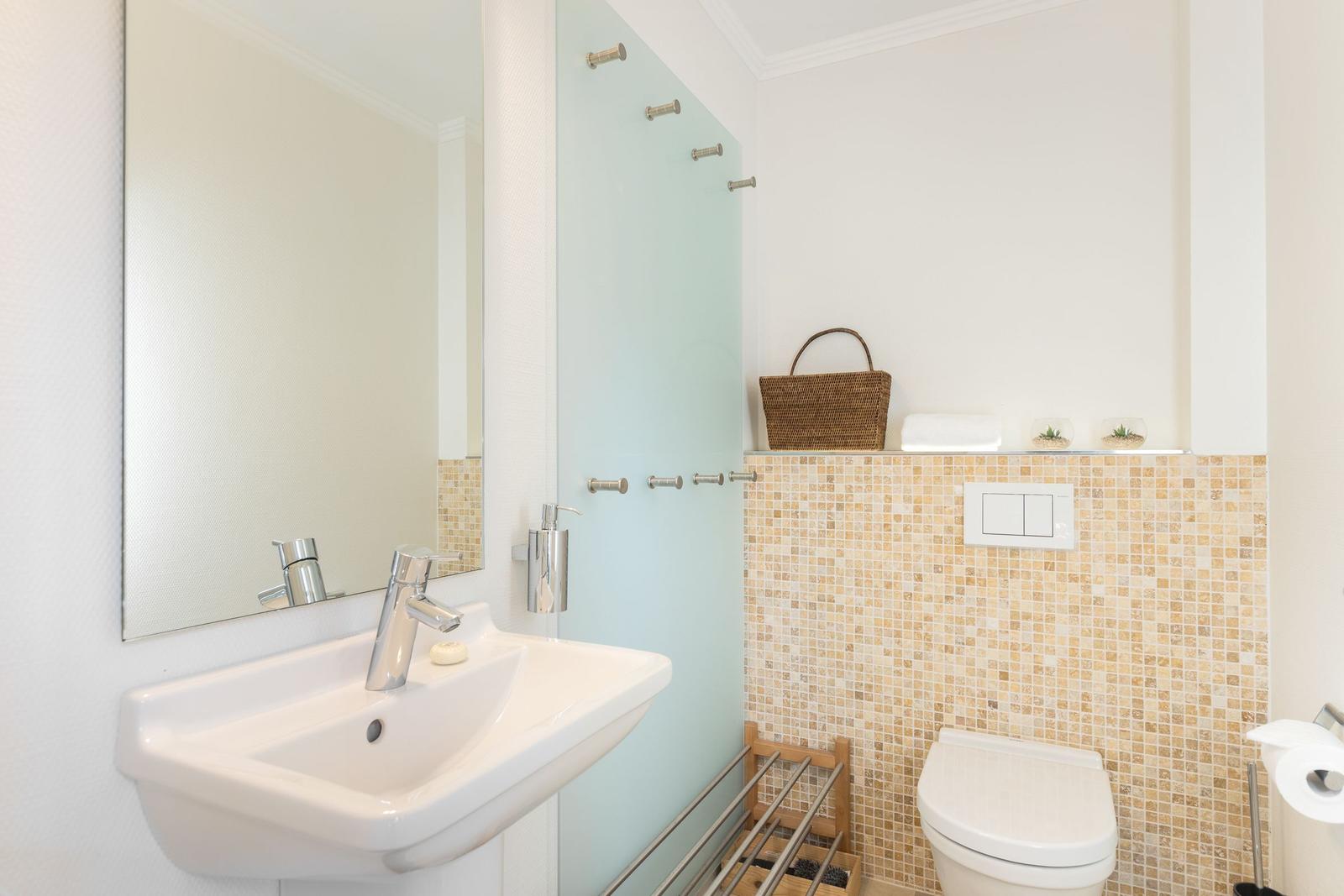 Badezimmer mit Waschbecken, Spiegel, Toilette und Mosaikwand