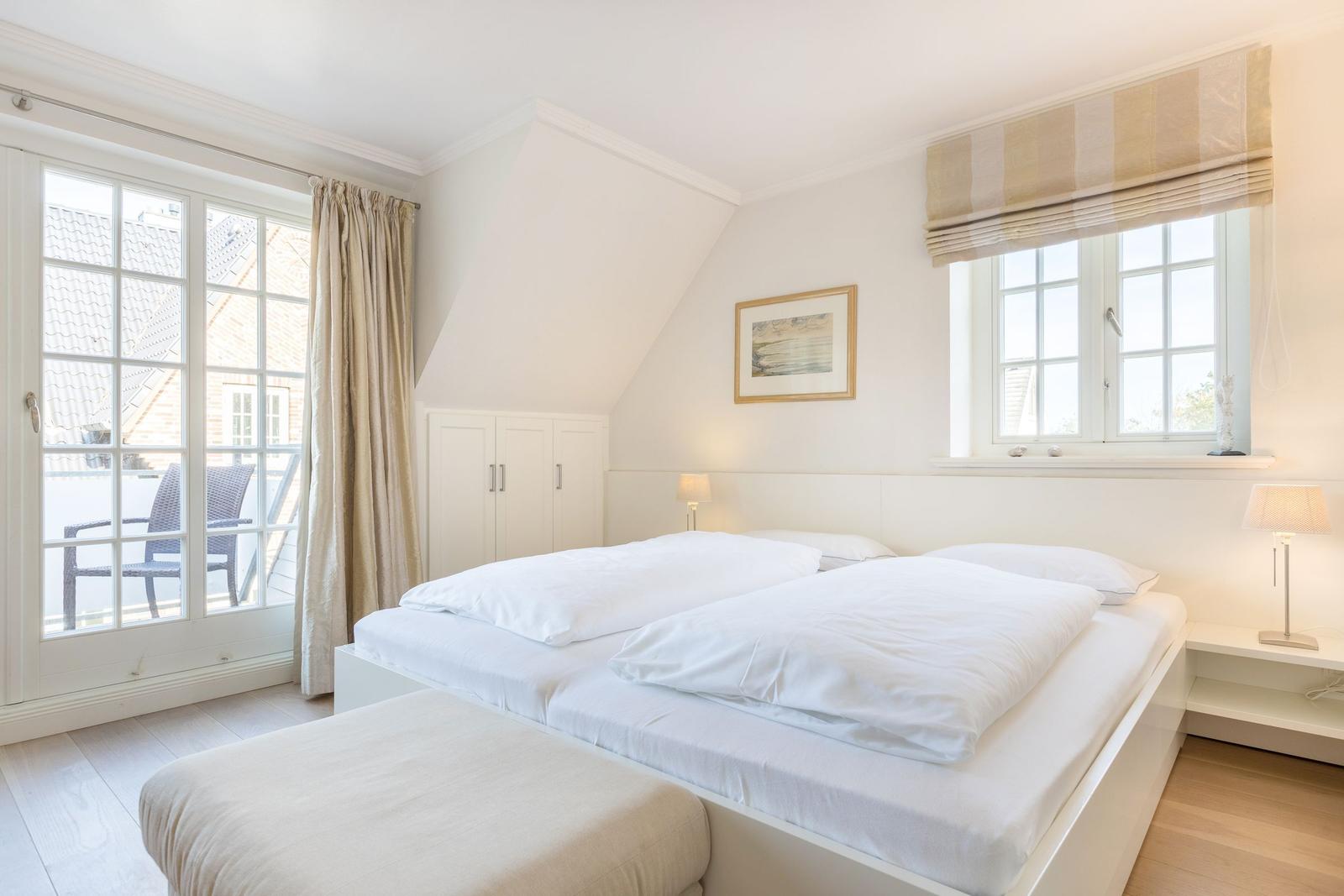 Schlafzimmer mit Doppelbett, Fenster und Balkonzugang.