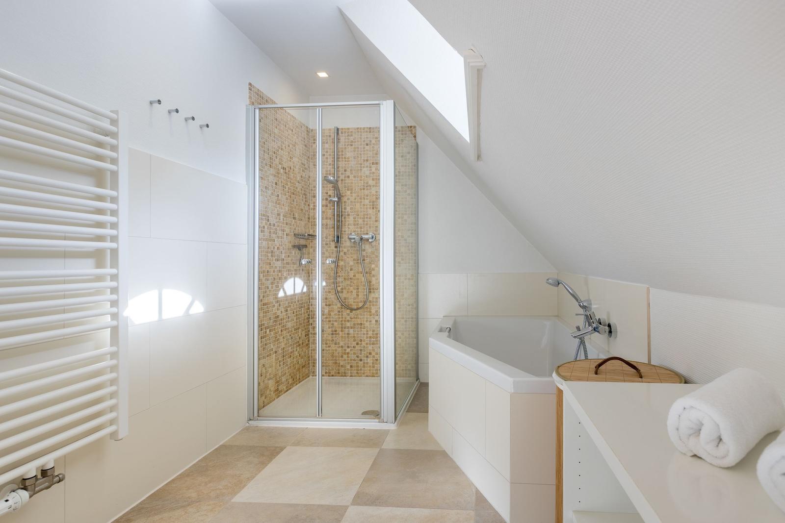 Badezimmer mit Dusche, Badewanne und Heizkörper unter Dachschräge