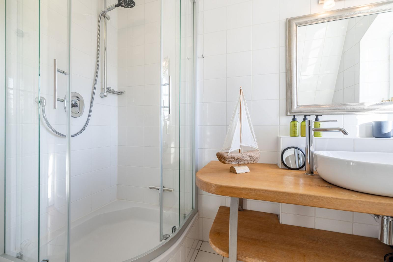 Dusche mit Glaswand, Waschtisch mit Holzplatte und Spiegel