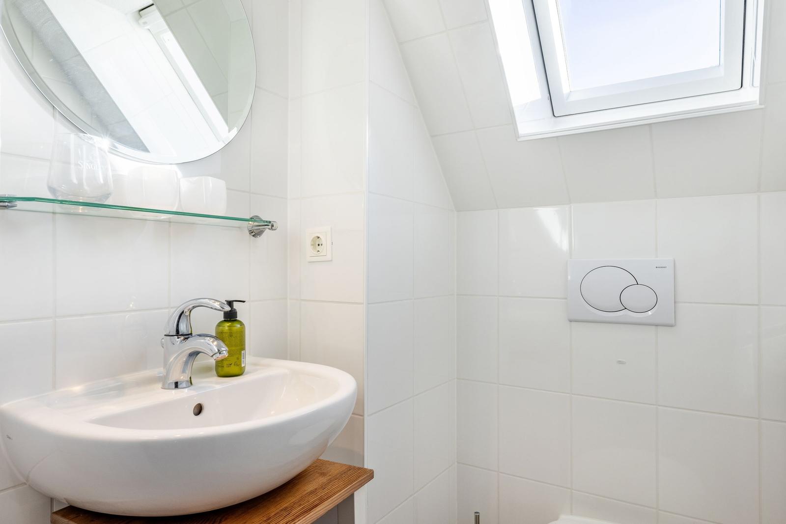 Badezimmer mit Waschbecken, Spiegel und Dachfenster