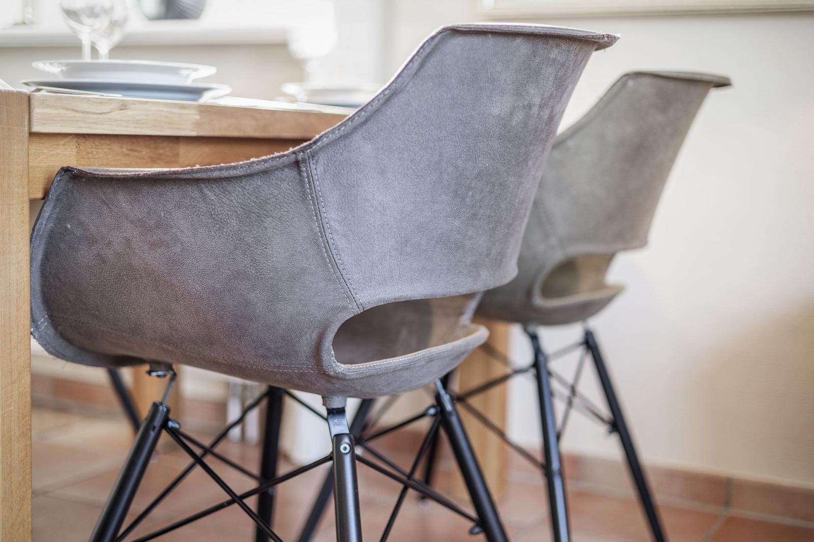 Zwei graue Sitzhocker mit schwarzen Metallbeinen stehen an einem Holztisch.