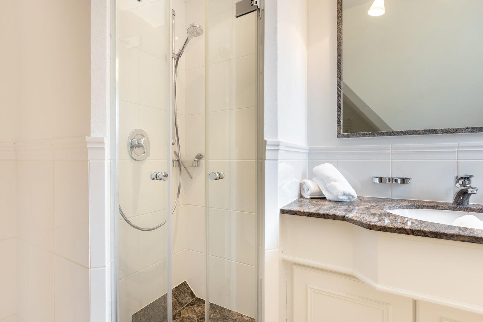 Shower with glass enclosure and sink with mirror