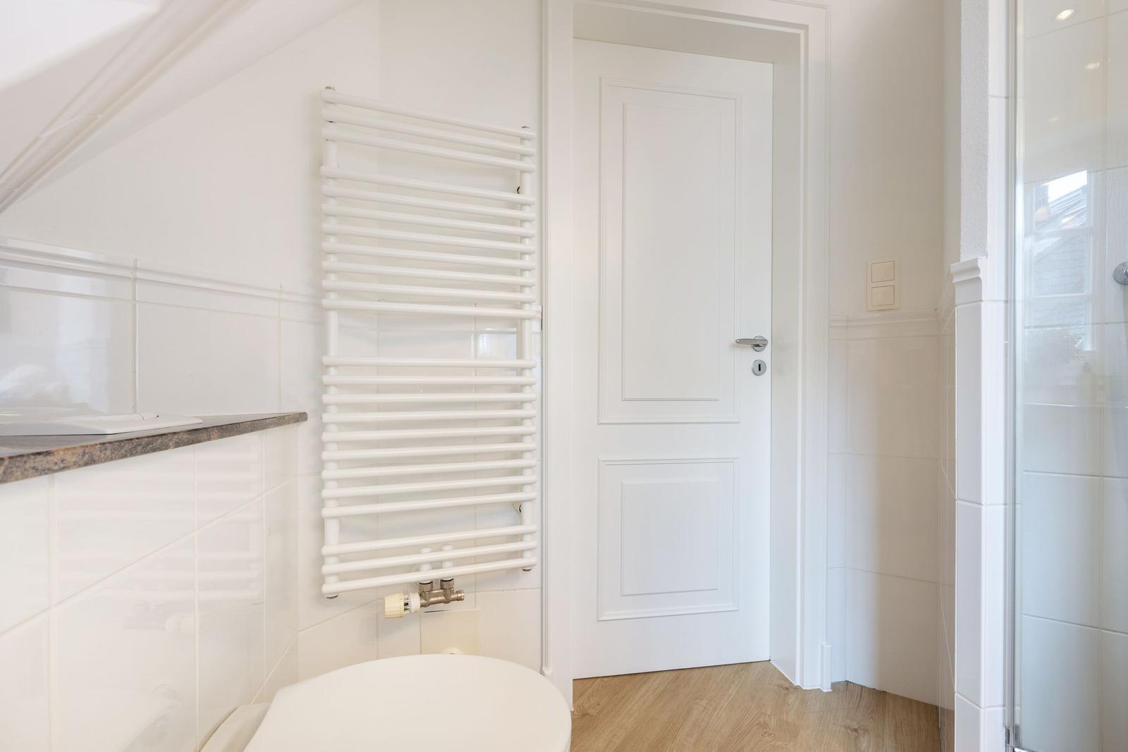 Bathroom with shower, toilet, and wall-mounted heater.