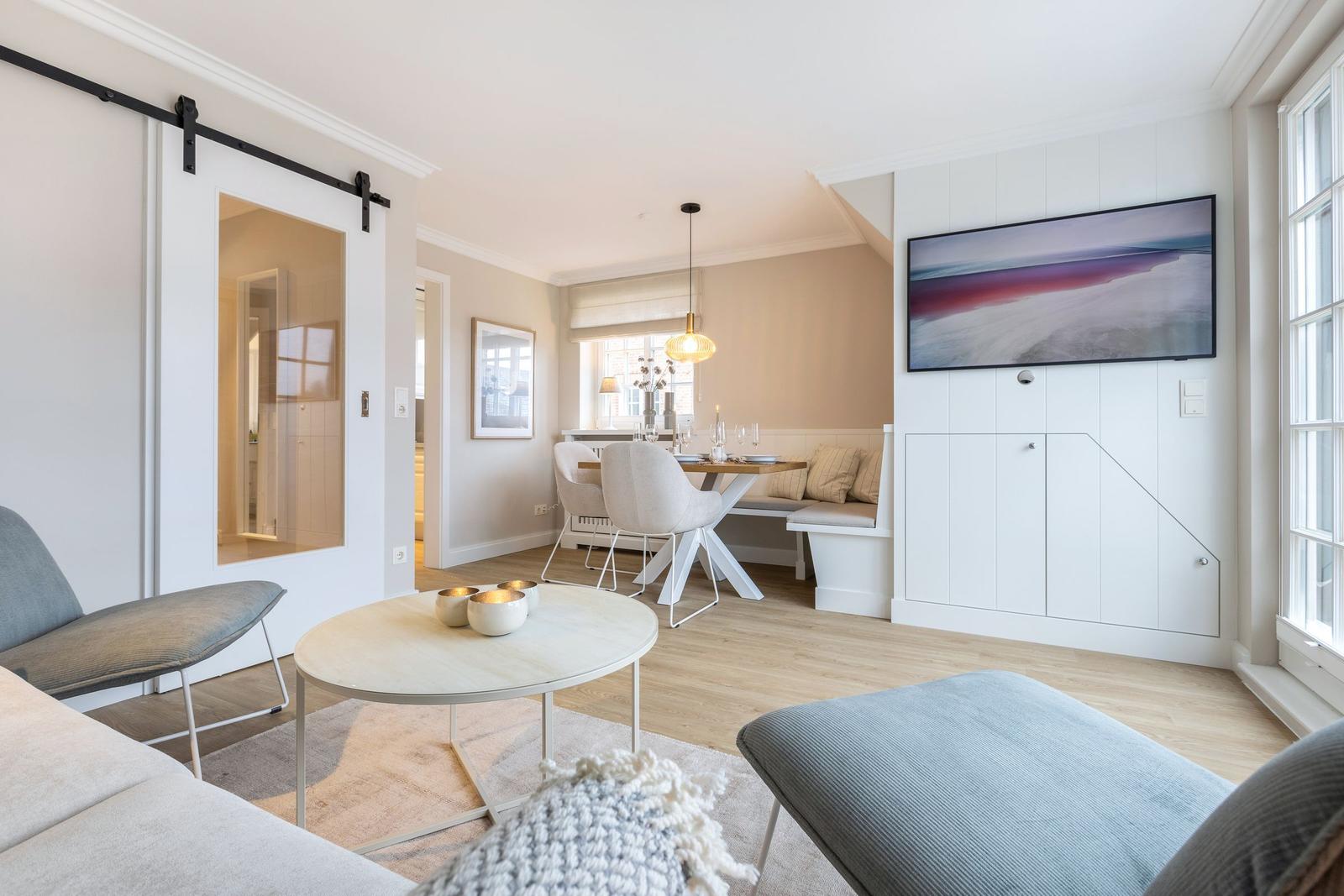 Living and dining area with modern furniture and large window.