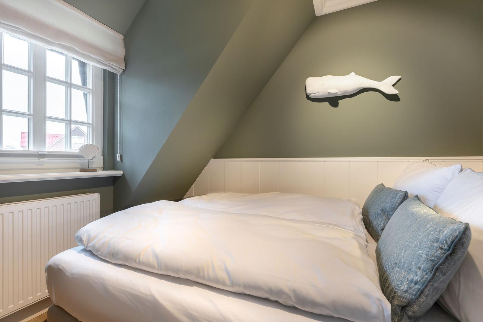 Bedroom with sloped ceiling, bed, and wall decoration.