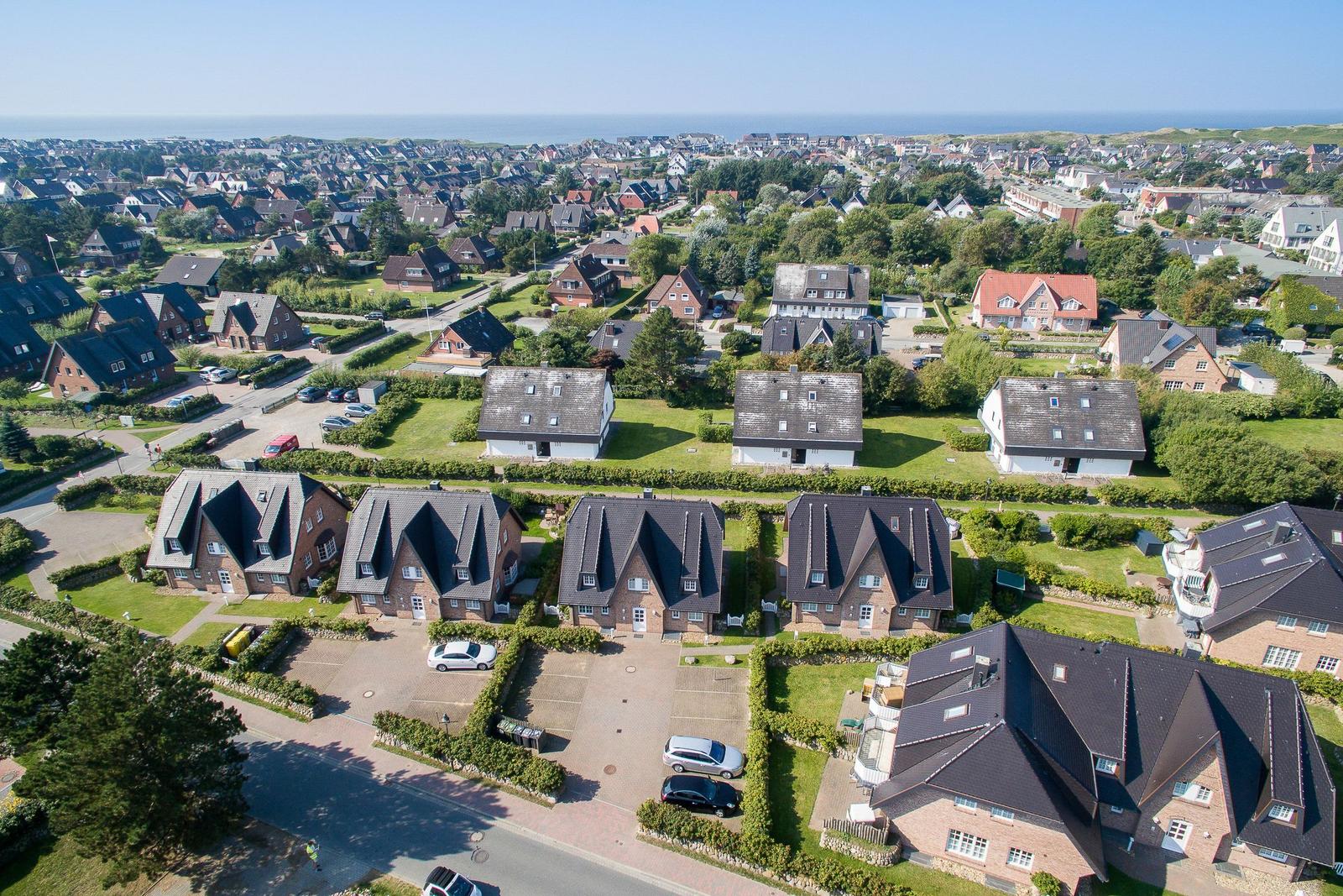 Aerial view of residential area with houses and greenery near the sea.