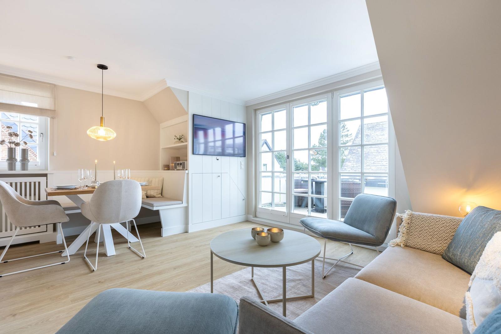 Living and dining area with TV, windows, and modern furniture.