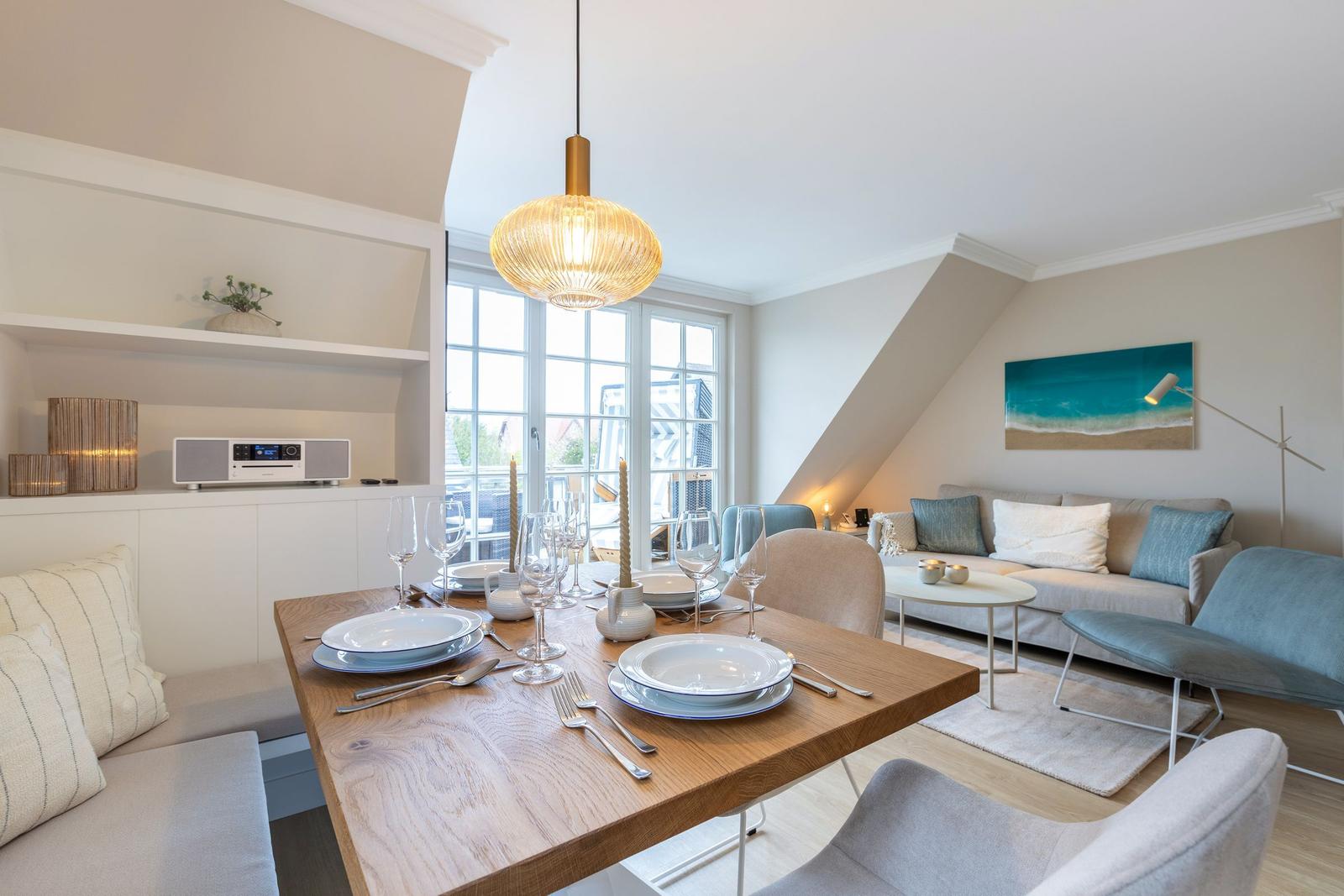 Dining room with table, chairs, and bench. Living area with sofa and wall art.
