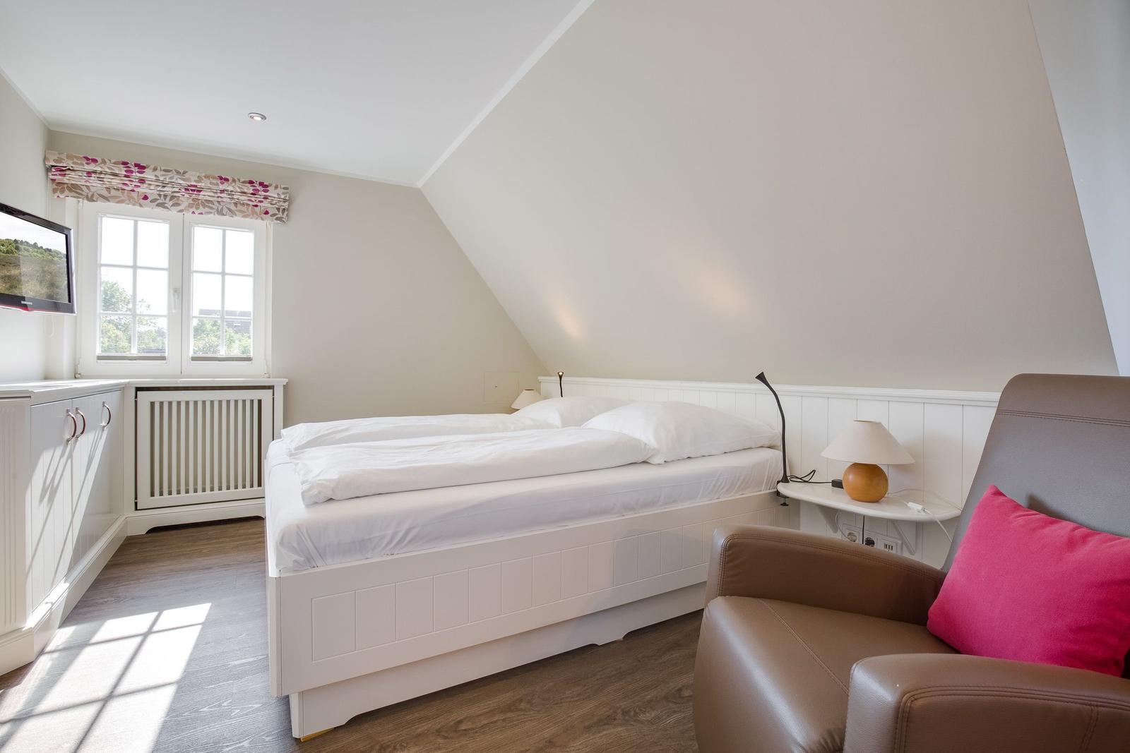 Schlafzimmer mit Doppelbett, Fenster und Sessel