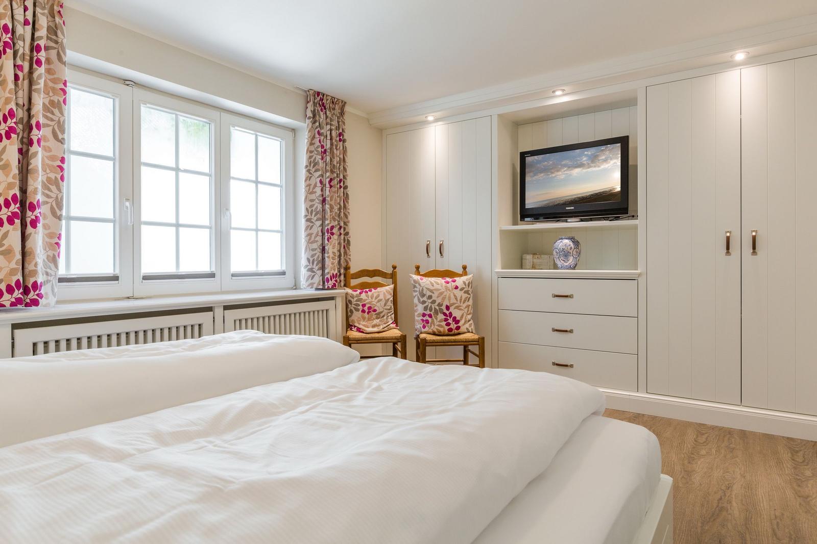 Schlafzimmer mit Doppelbett, Fenster, TV und Schrank