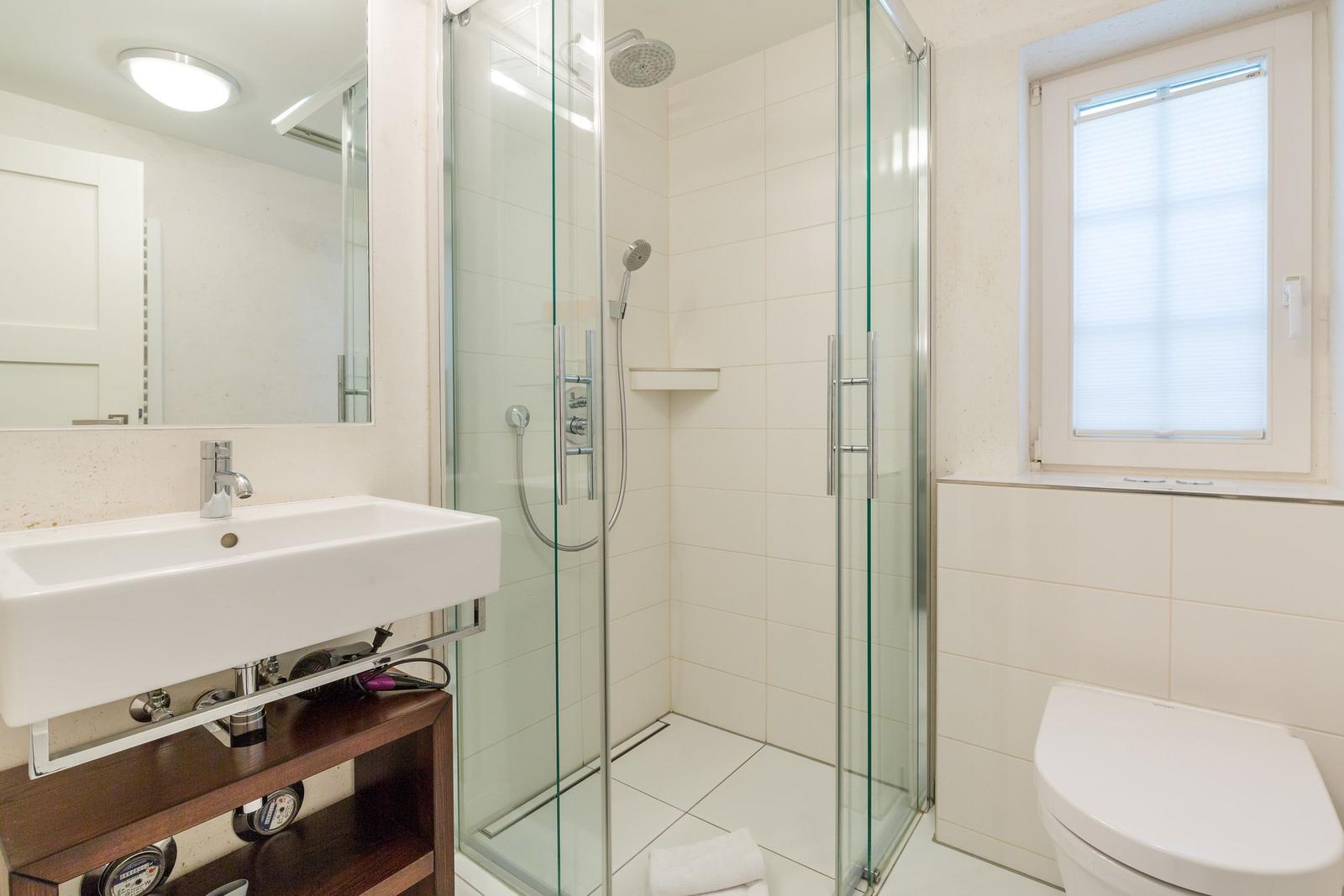 Badezimmer mit Dusche, Waschbecken und Toilette.
