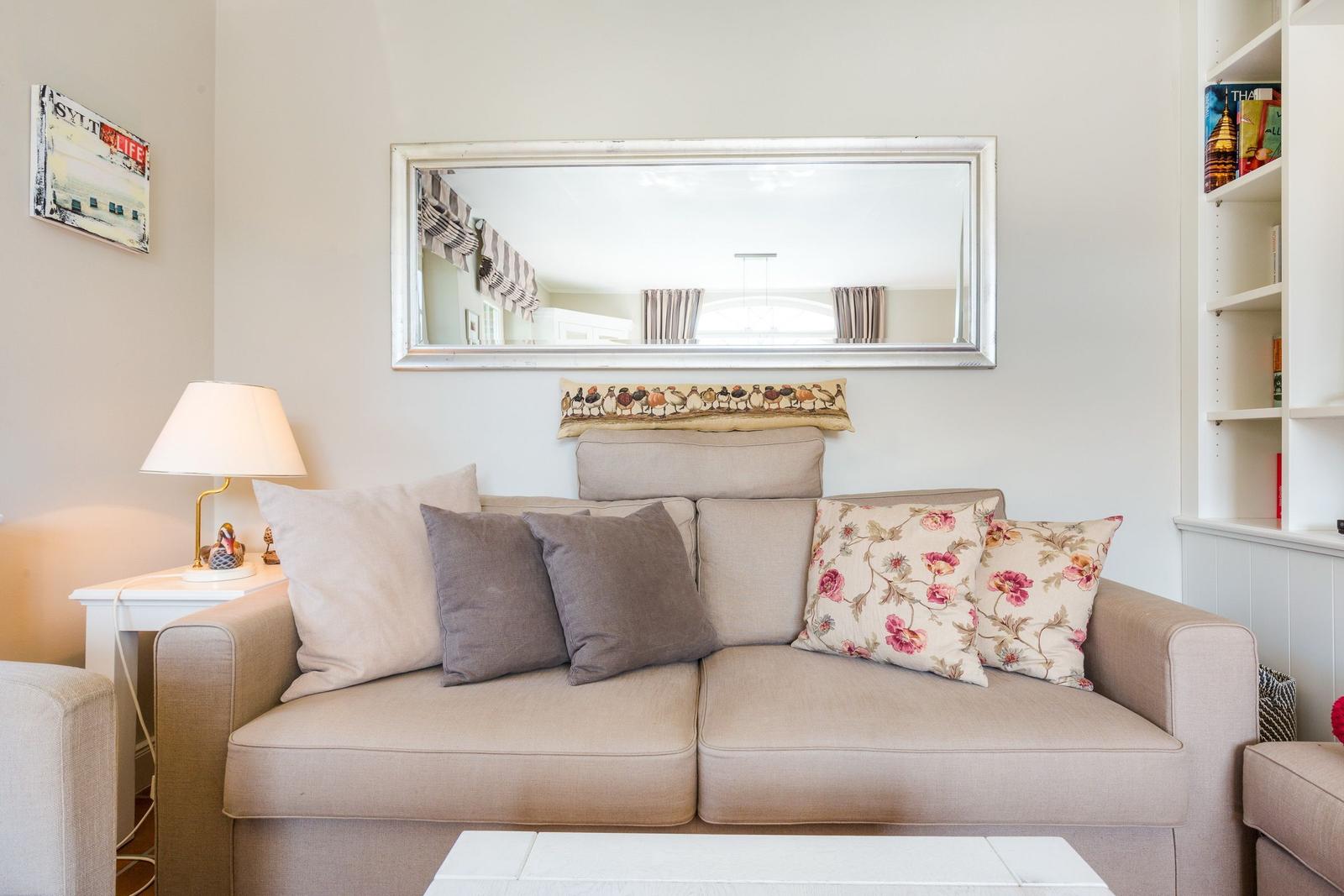 Ein Sofa mit Kissen, Spiegel und Beistelltisch im Wohnzimmer.