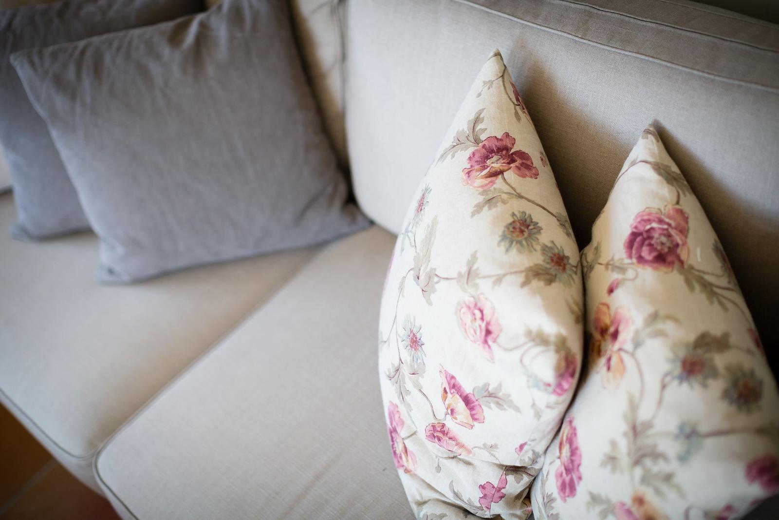 Ein Sofa mit zwei floralen Kissen und zwei grauen Kissen.