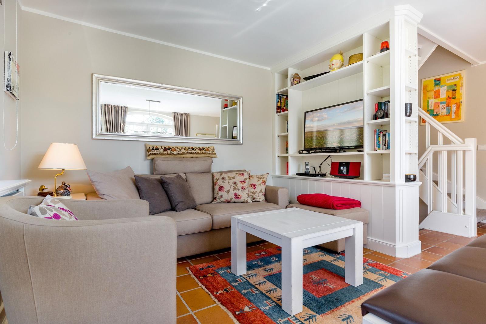 Wohnzimmer mit Sofa, Couchtisch und Fernseher an Wandregal