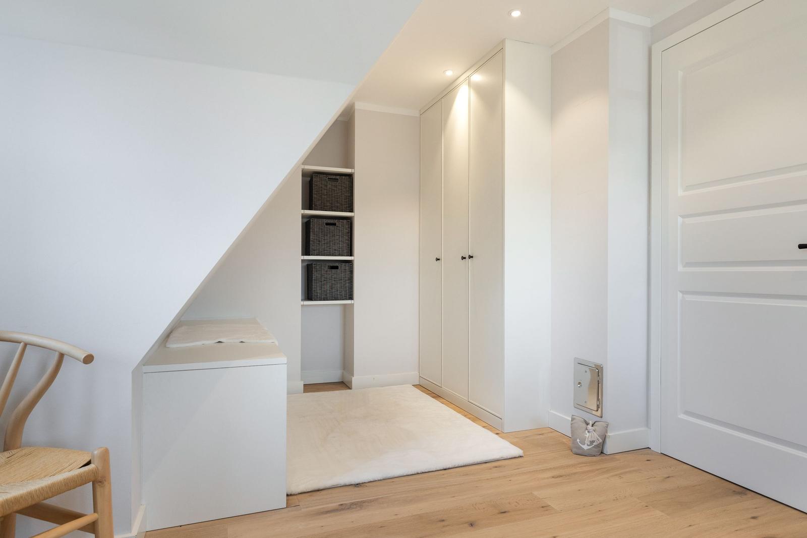 Bedroom with wardrobe, shelves, and wooden floor.