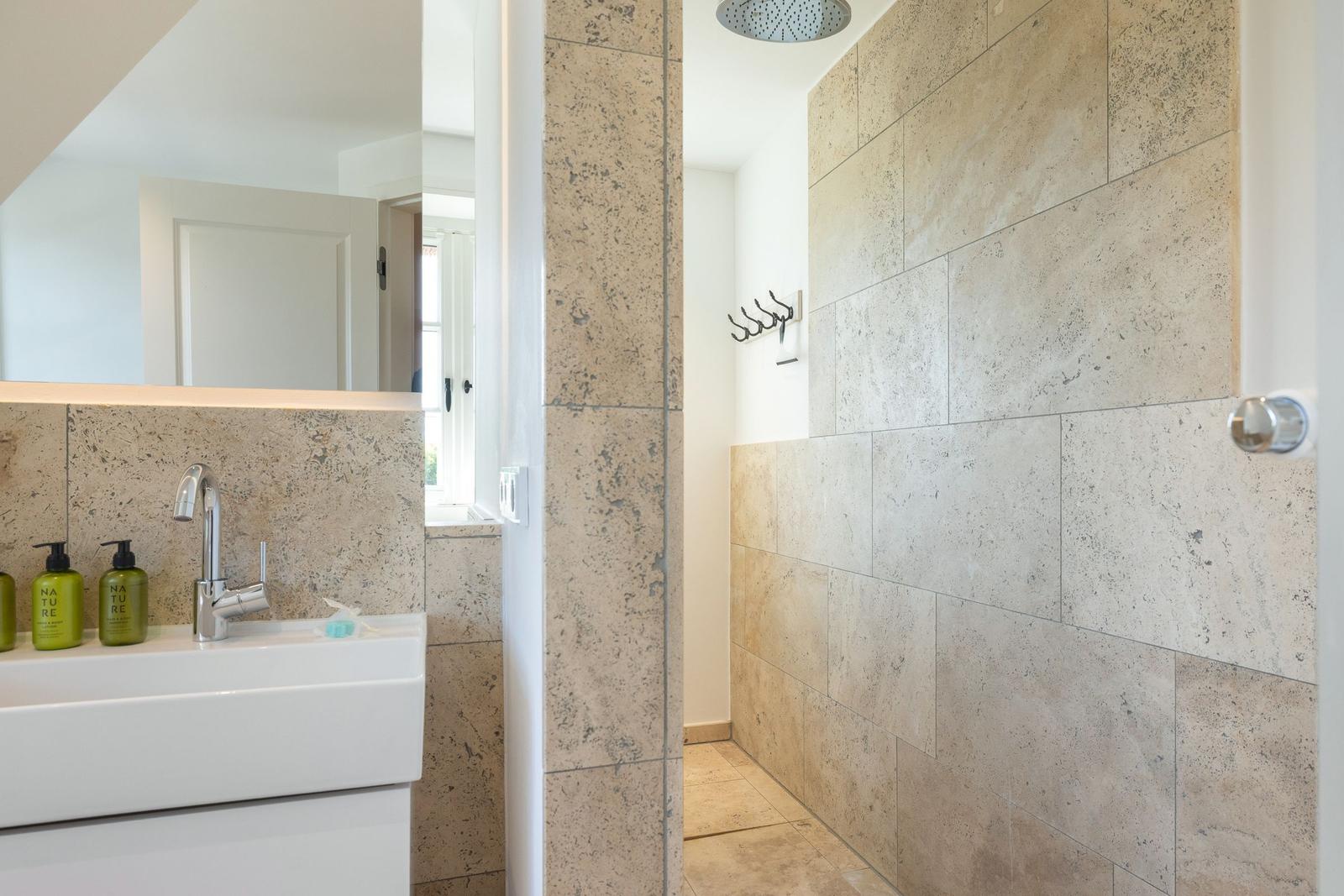 Bathroom with stone wall, shower, and sink with mirror