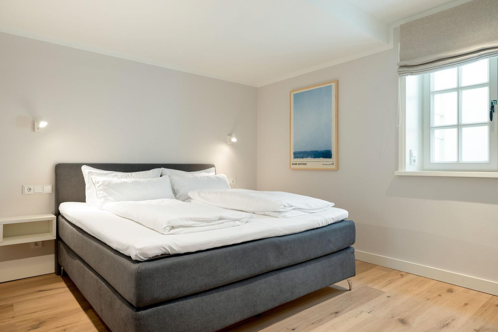 A bedroom with a bed, a window, and wall decor.