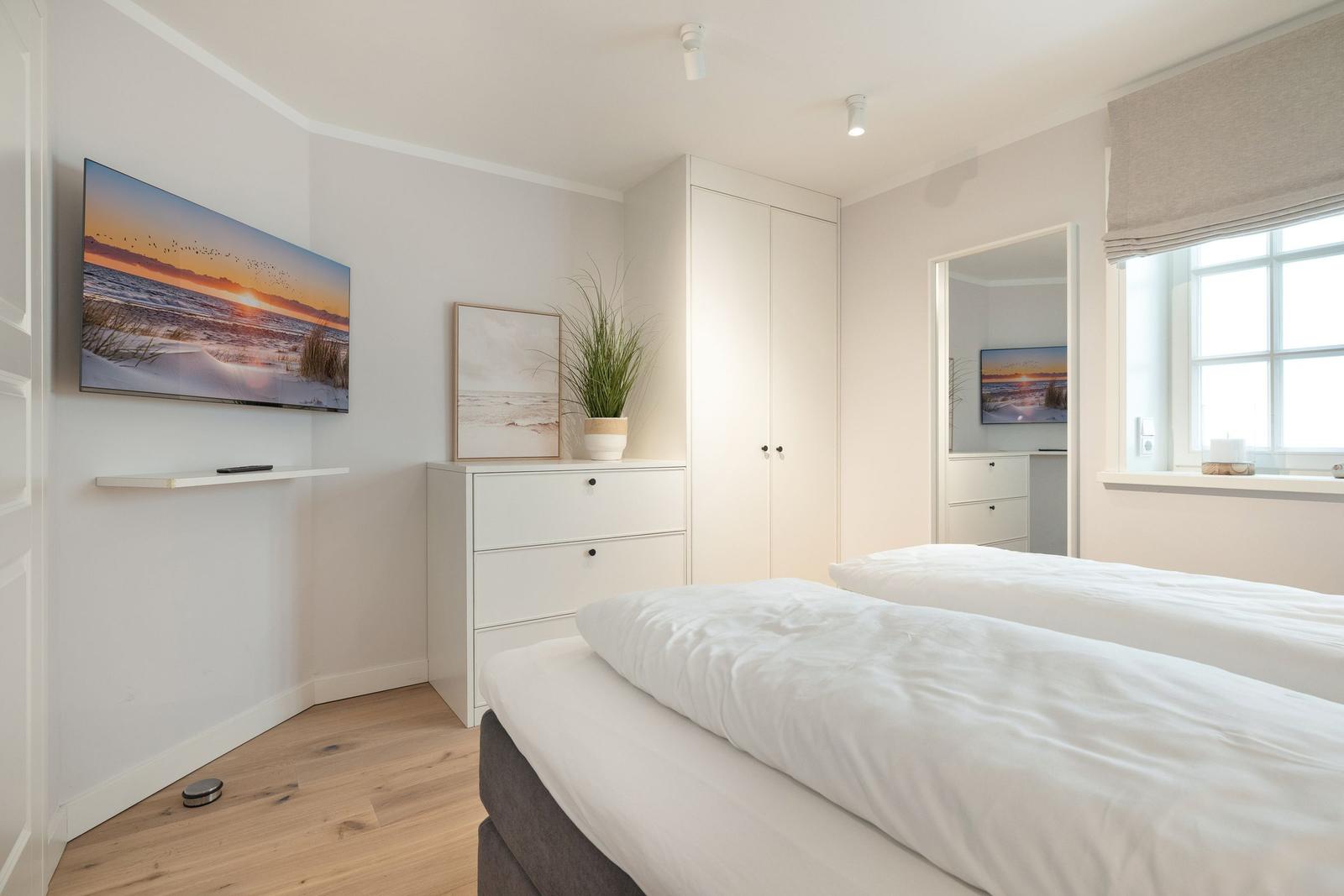 Bedroom with double bed, wardrobe, and TV mounted on the wall.