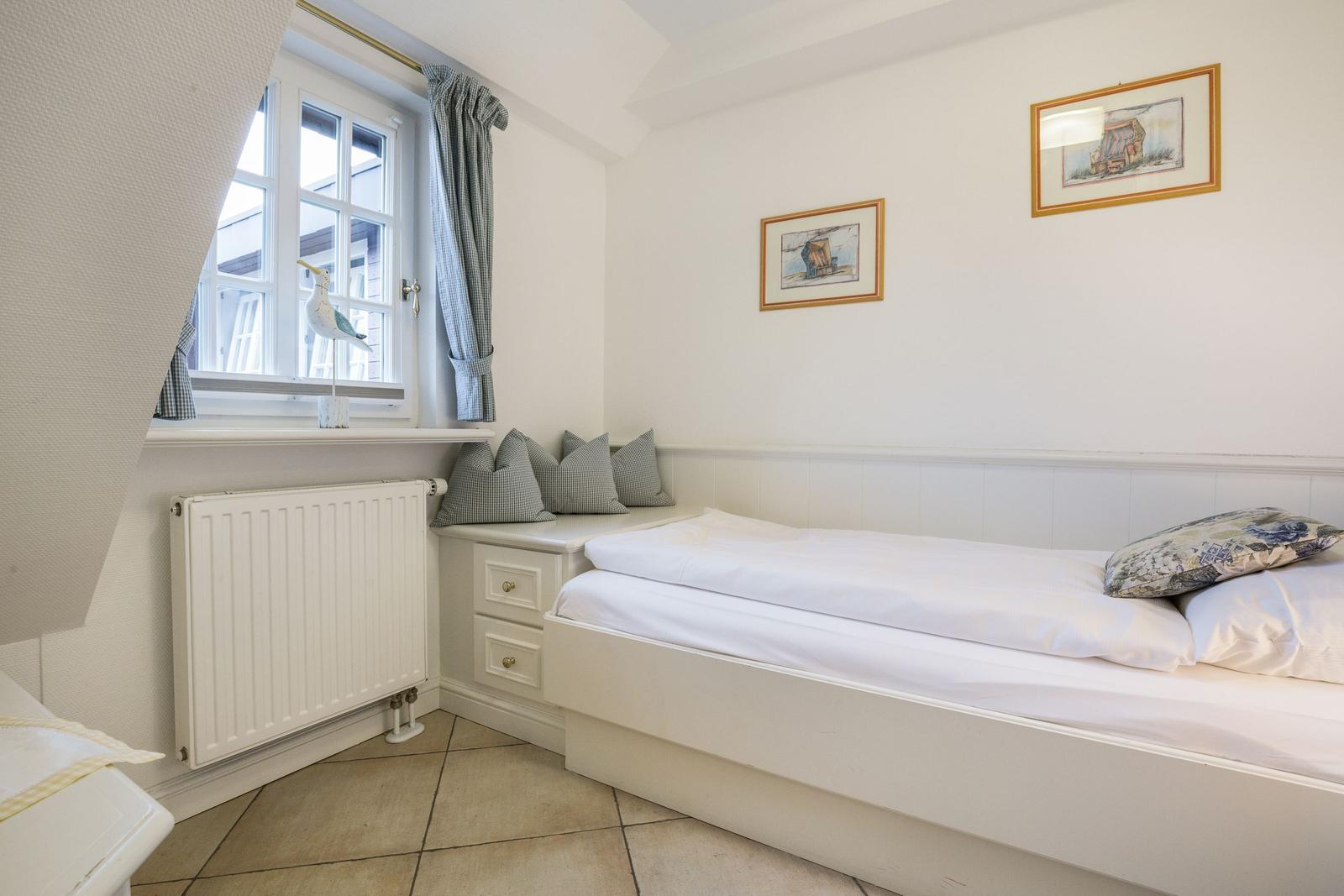 Bedroom with white bed, window, and wall pictures