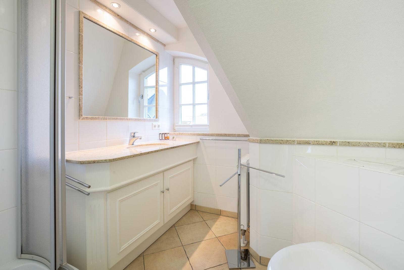 Bathroom with sink, mirror, and shower under sloped ceiling.