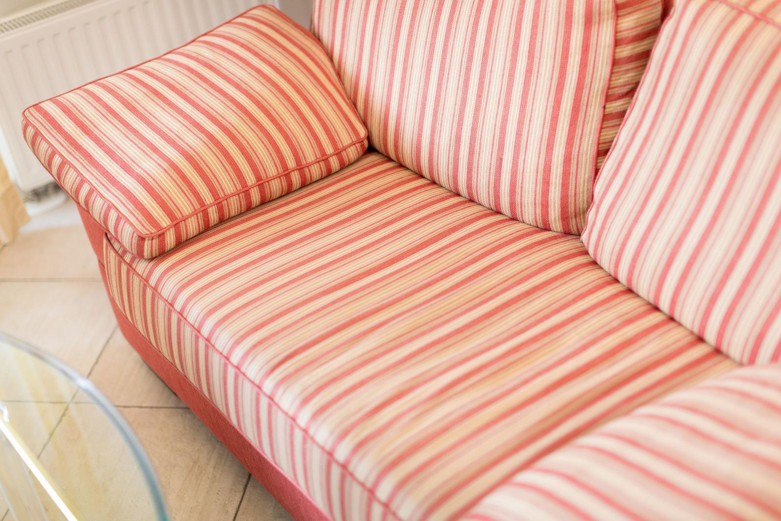 A sofa with striped upholstery in red-beige tones.