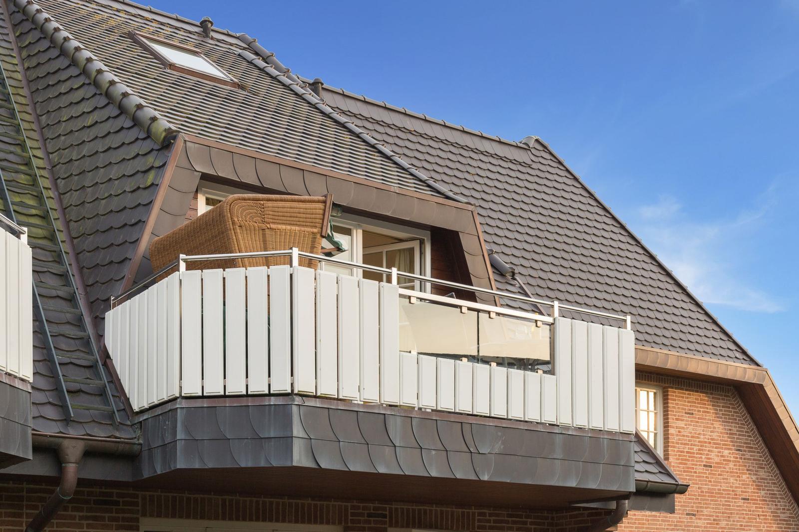 Attic balcony with white railing and wicker furniture