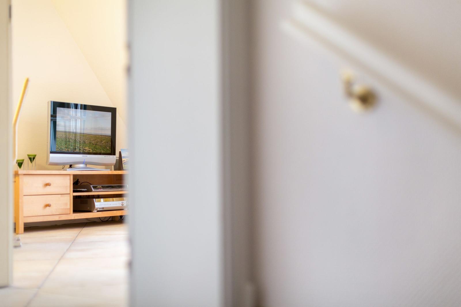 TV on wooden stand in bedroom with light walls