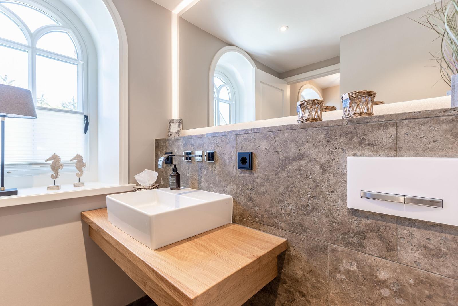 Bathroom with sink on wooden vanity, stone wall, and mirror