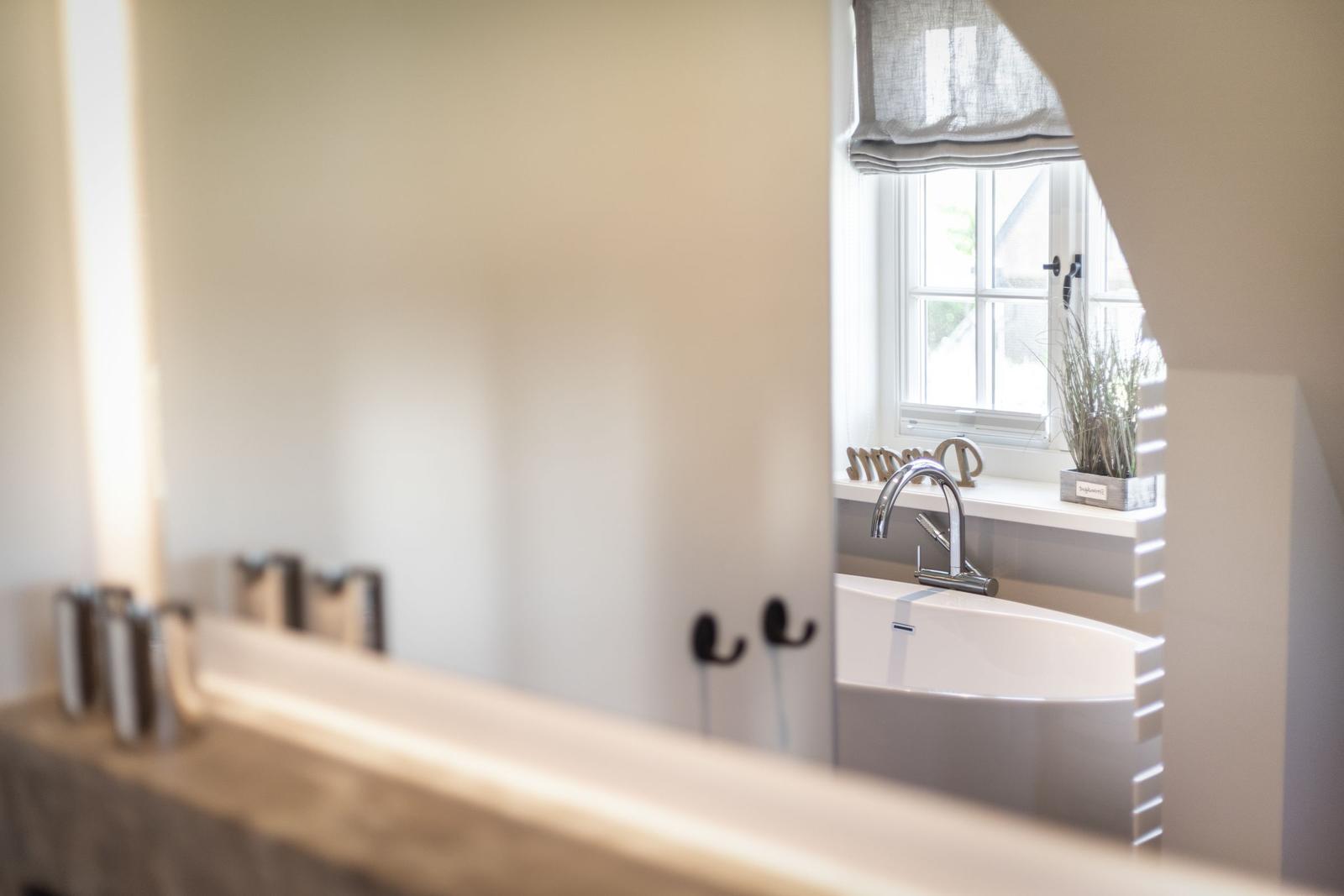 Bathroom with bathtub, window, and plant on the sill.