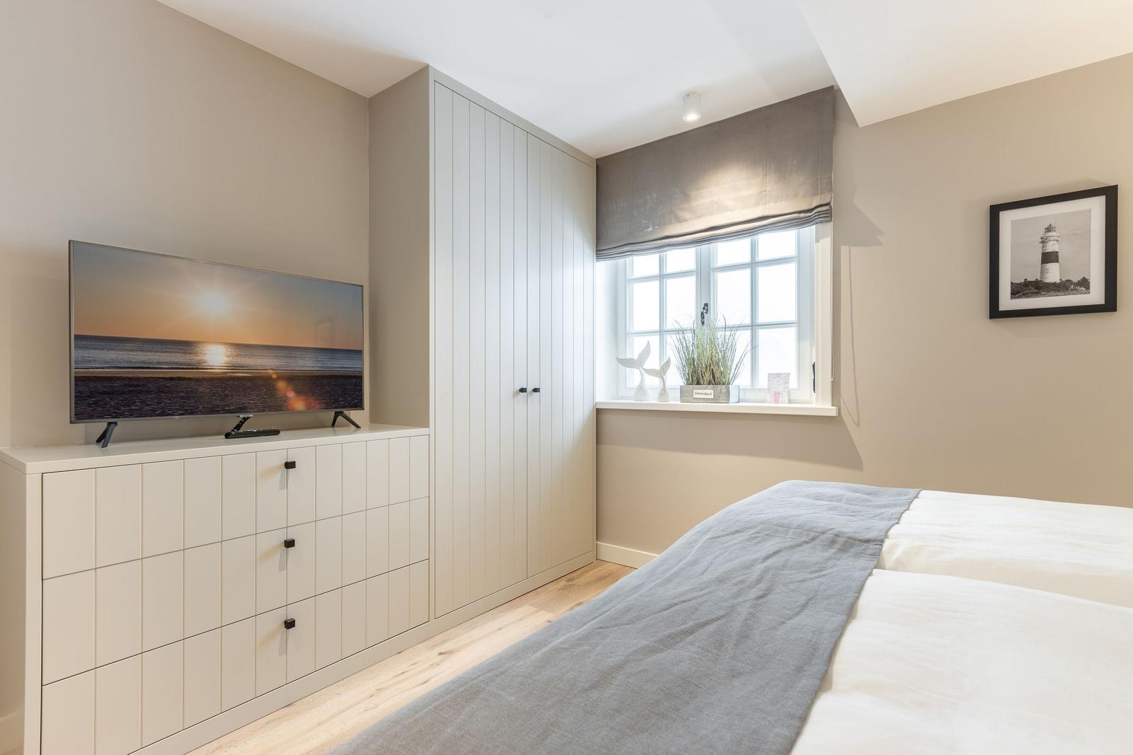 Bedroom with bed, wardrobe, TV, and window with view.