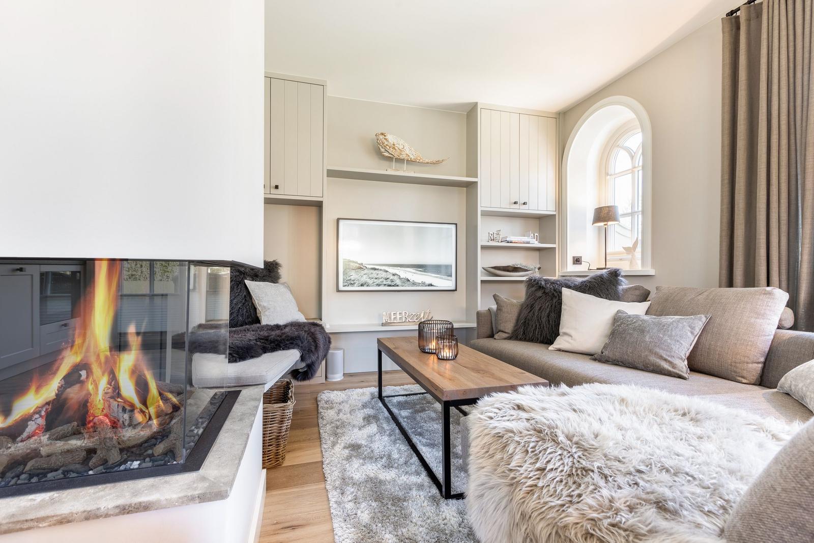 Living room with fireplace, sofa, and wooden table. Arched window and decorative elements.