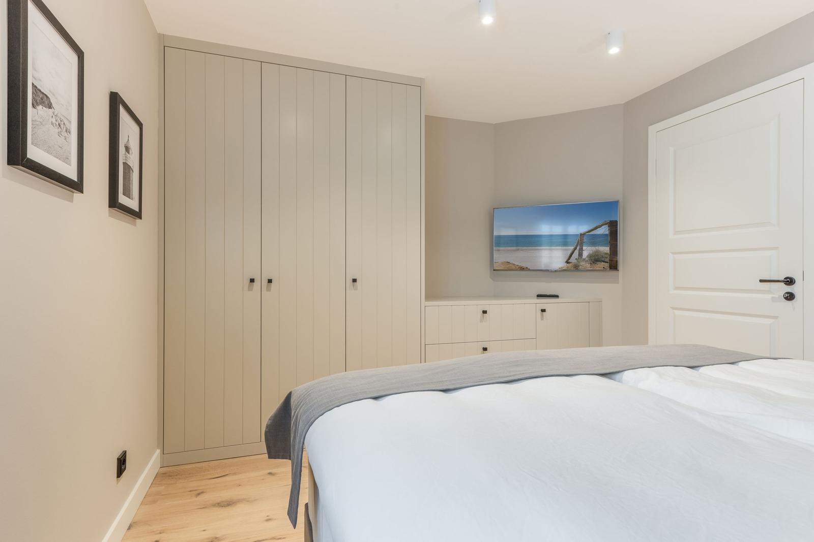 Bedroom with bed, wardrobe, and TV mounted on the wall.