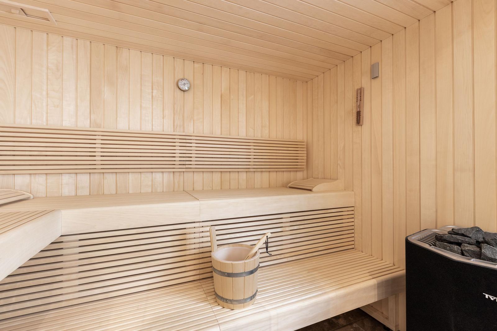 Sauna with wooden bench, thermometer, and stone heater
