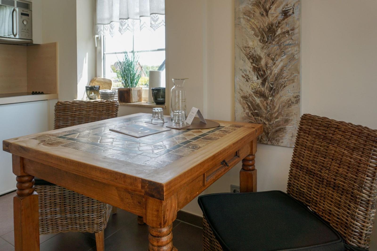 Dining room with wooden table, wicker chairs, and window view.