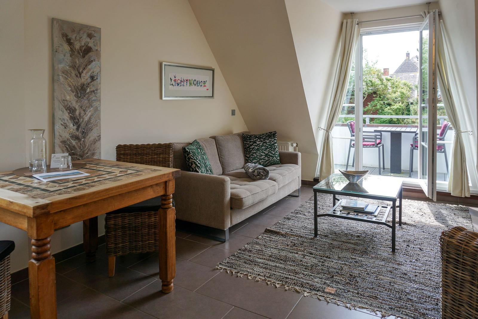 Living room with sofa, table, and terrace. Glass door opens to outdoor terrace.