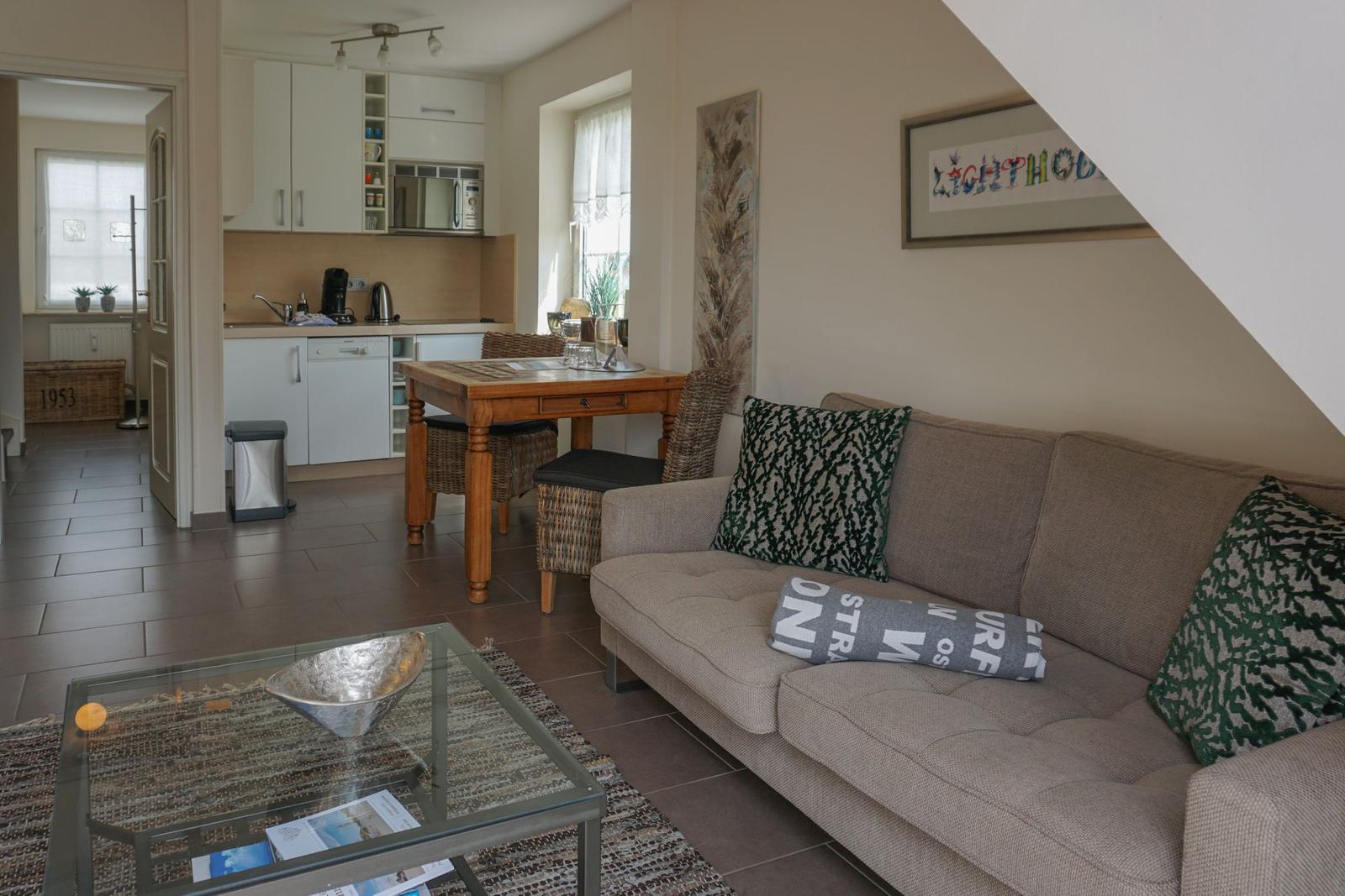 Living room with sofa, glass table, and view into the kitchen
