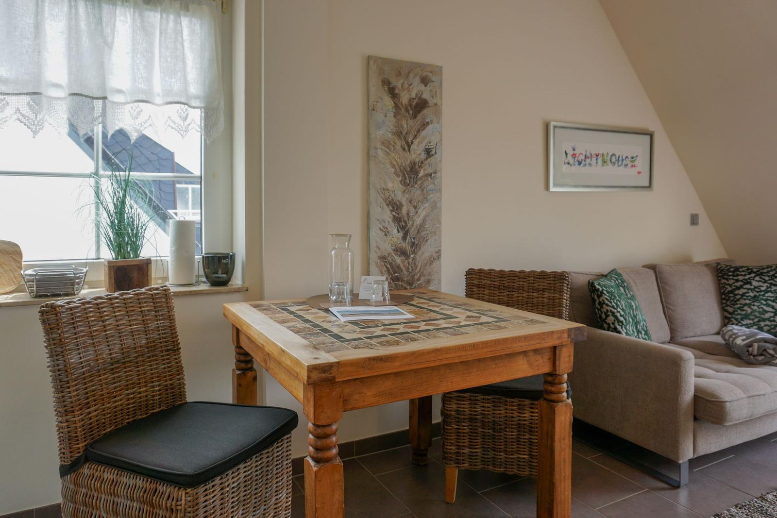 Dining room with wooden table, wicker chairs, and sofa under sloped ceiling.