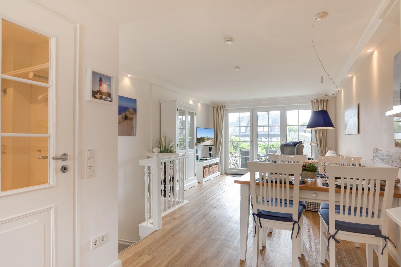 Dining area with table and chairs, living area with TV and window to terrace.