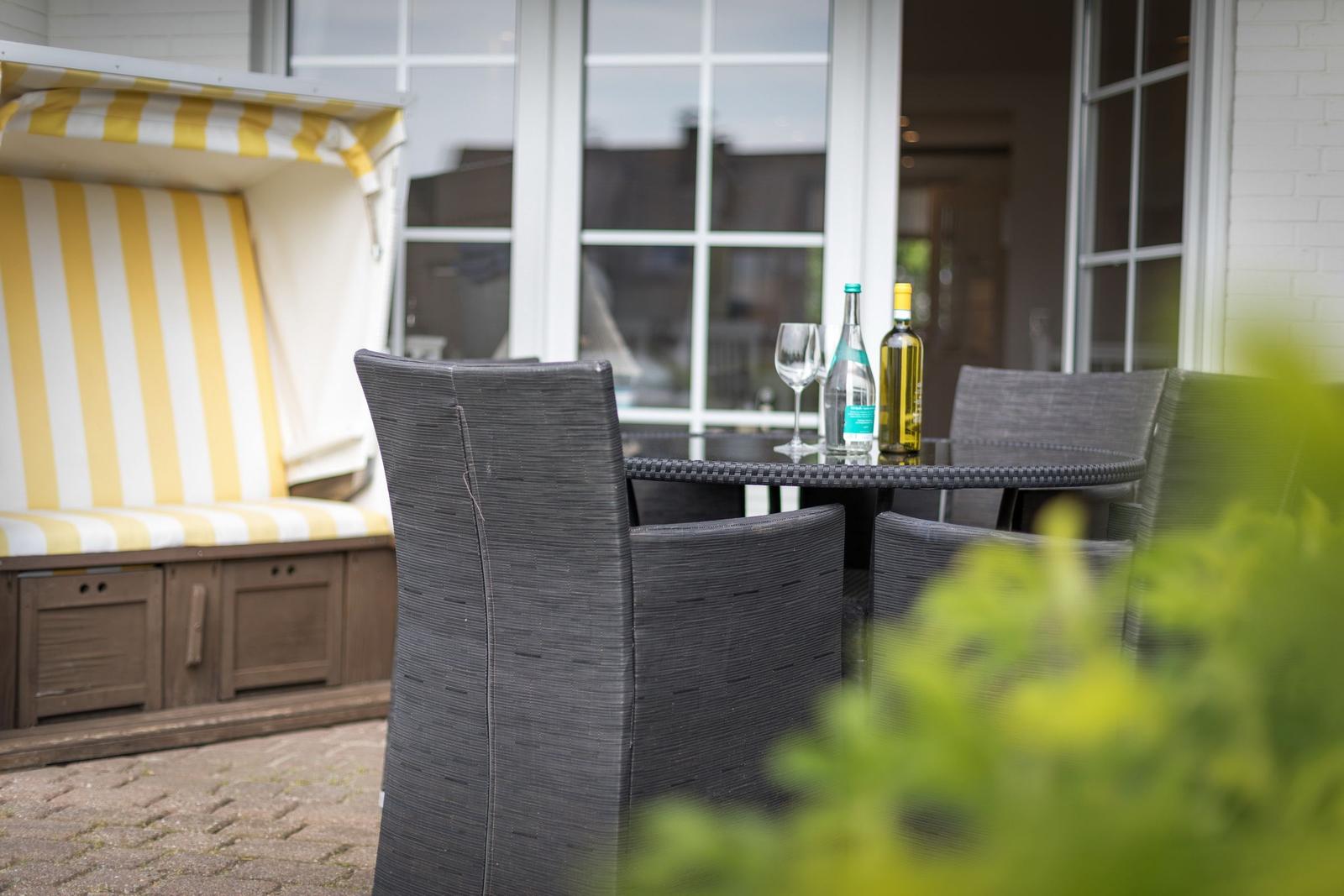 Terrace with dining table, chairs, and beach cabana with yellow-white stripes.