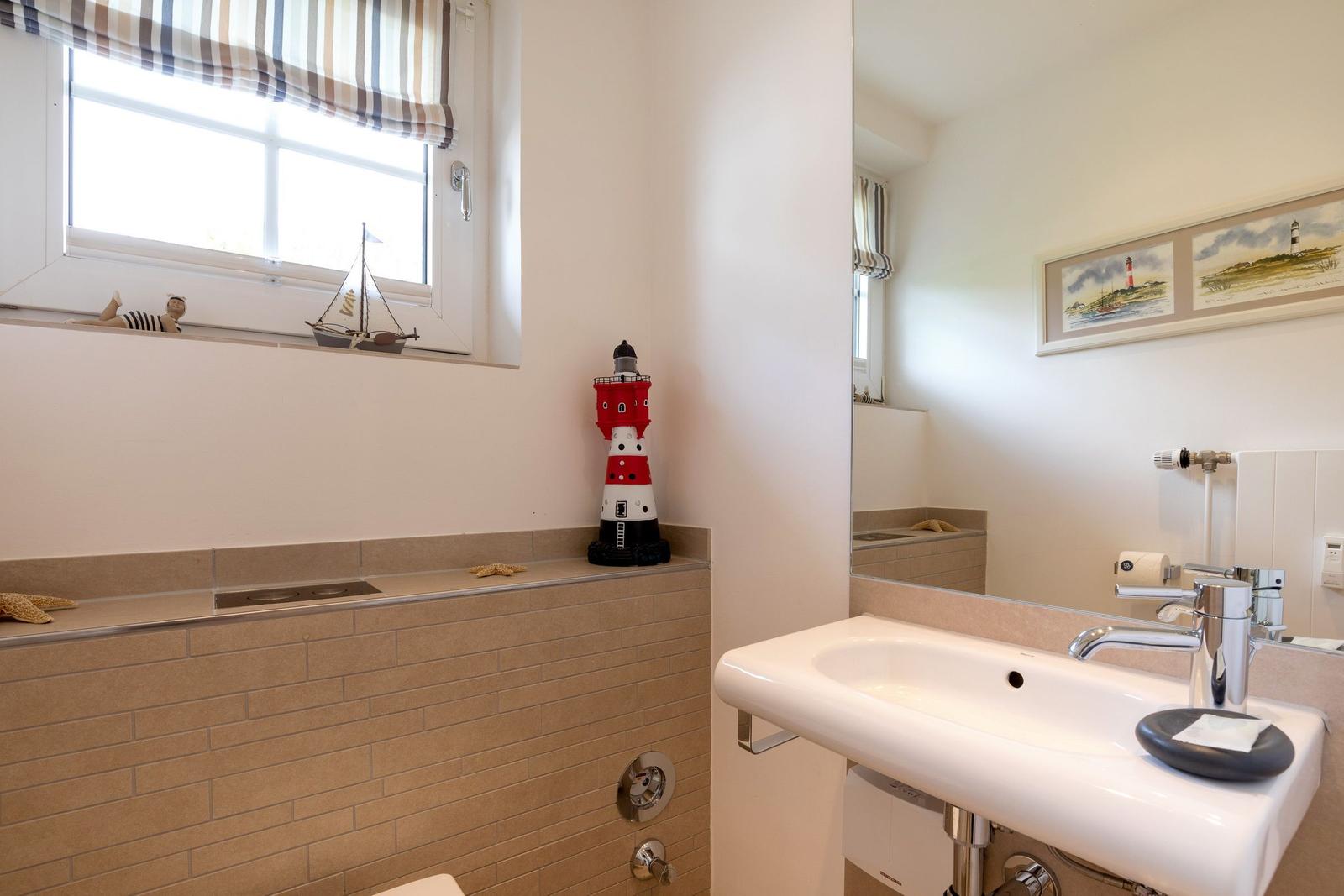 Bathroom with sink, mirror, window, and red lighthouse model.