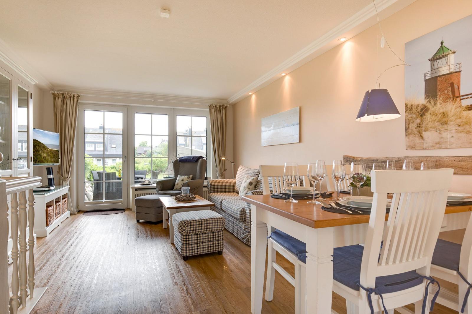 Living and dining area with hardwood floor, TV, table with chairs, and balcony view.