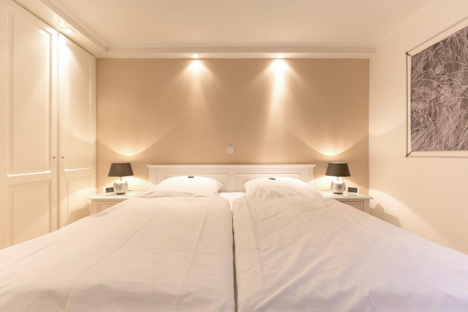 Double bed with white bedding, nightstands with lamps and wall art