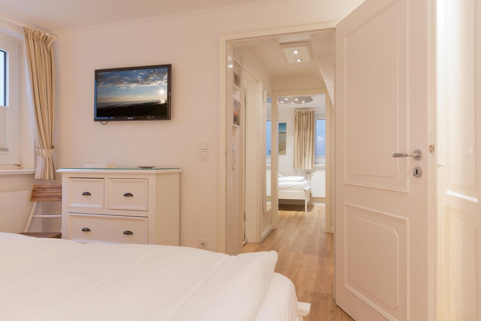 Bedroom with TV and view into adjacent room.