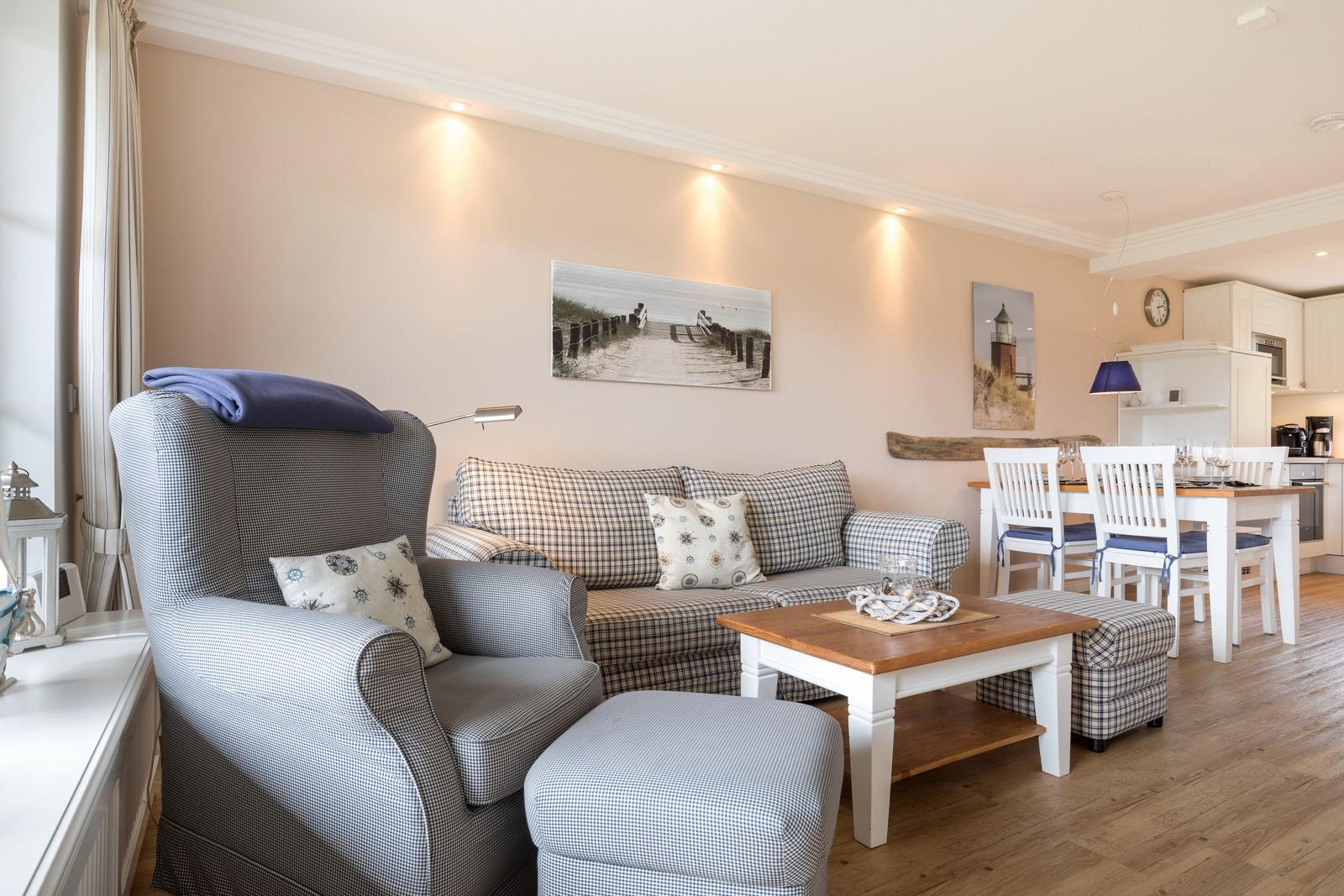 Living and dining area with sofa, armchair, and table.